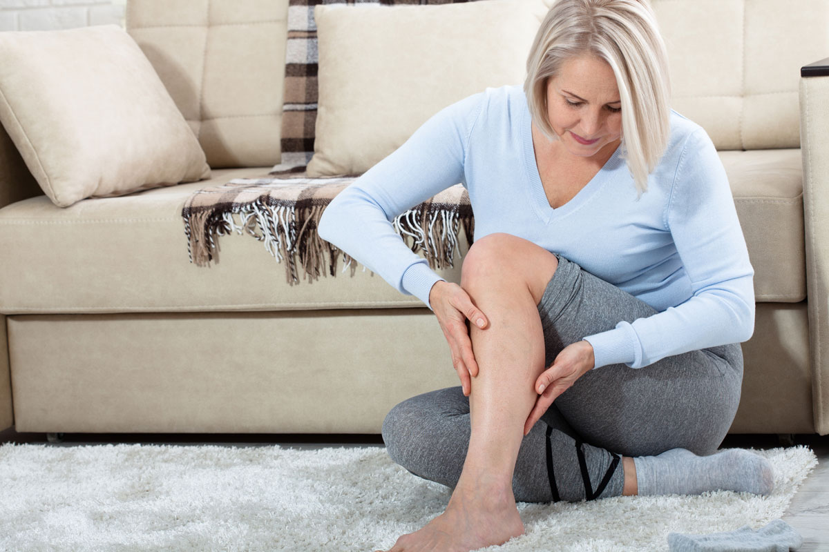 Personne qui se masse les mollets assise, illustration du mal aux jambes en fin de journée